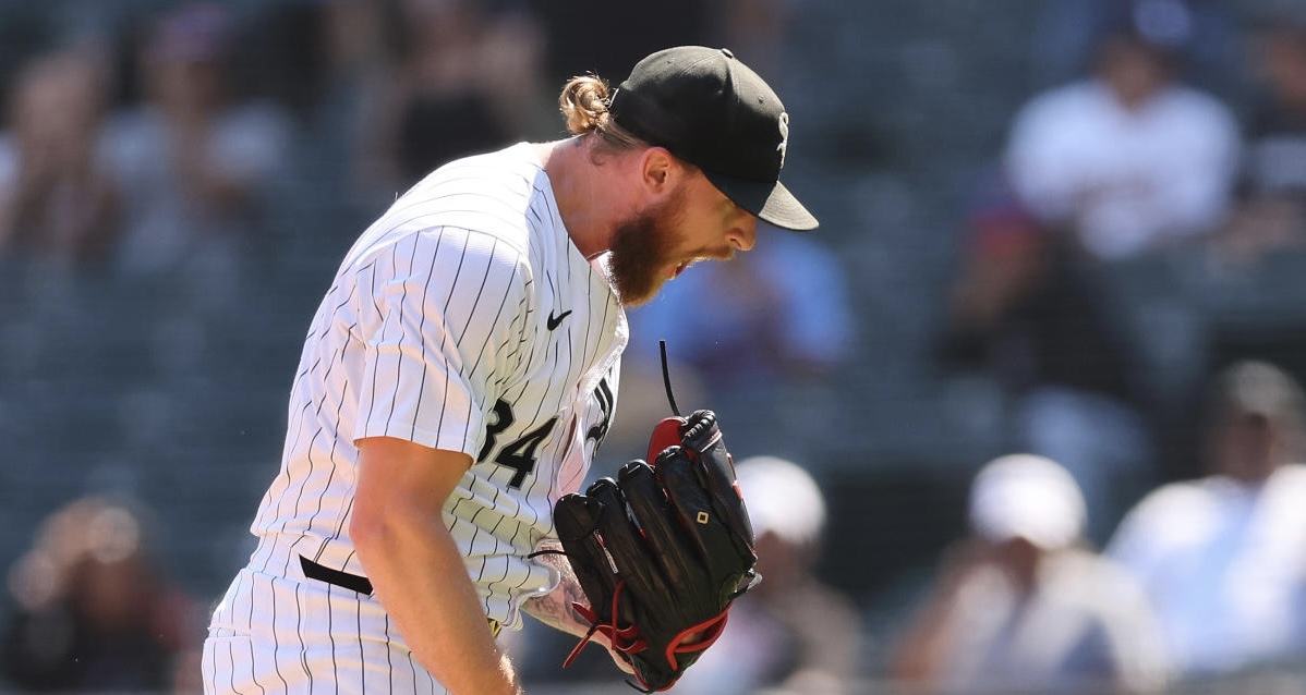 Lanzador de los Medias Blancas en uniforme blanco con pinstripes lanza la pelota durante un juego, con guante rojo y gorra negra