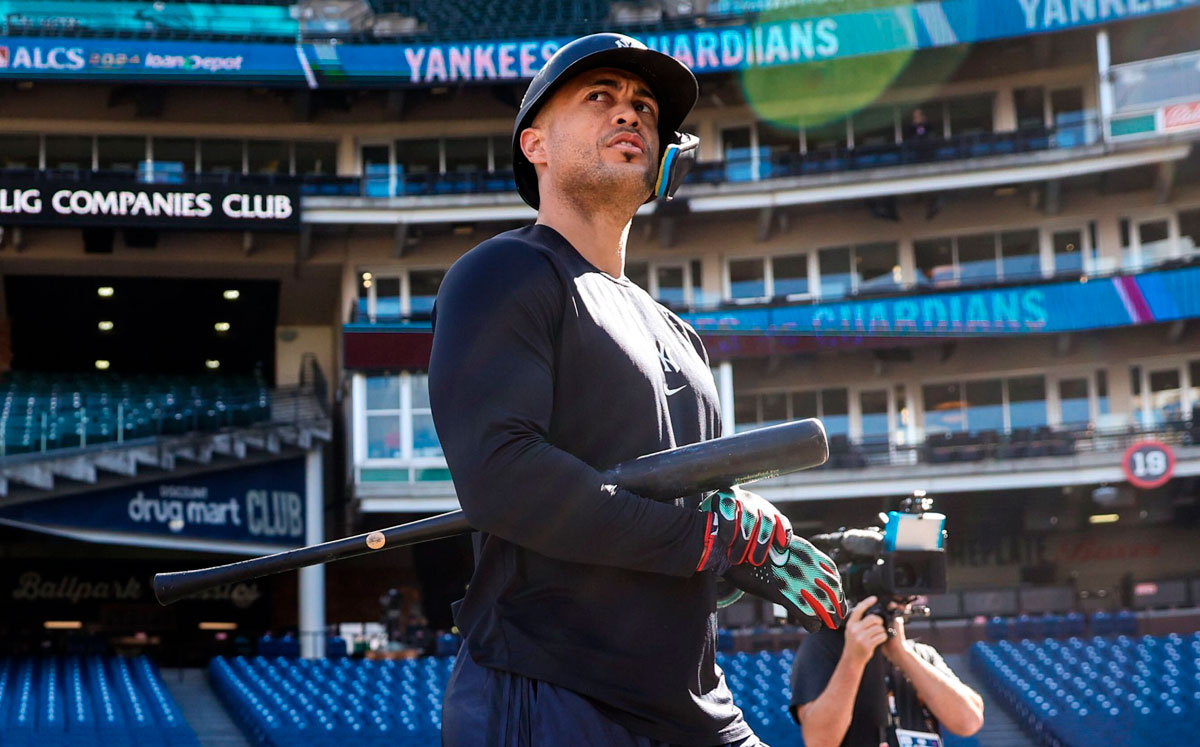 Pelotero con uniforme azul marino de los Yankees en el cajón de bateo, sosteniendo el bate y mirando hacia arriba en el estadio