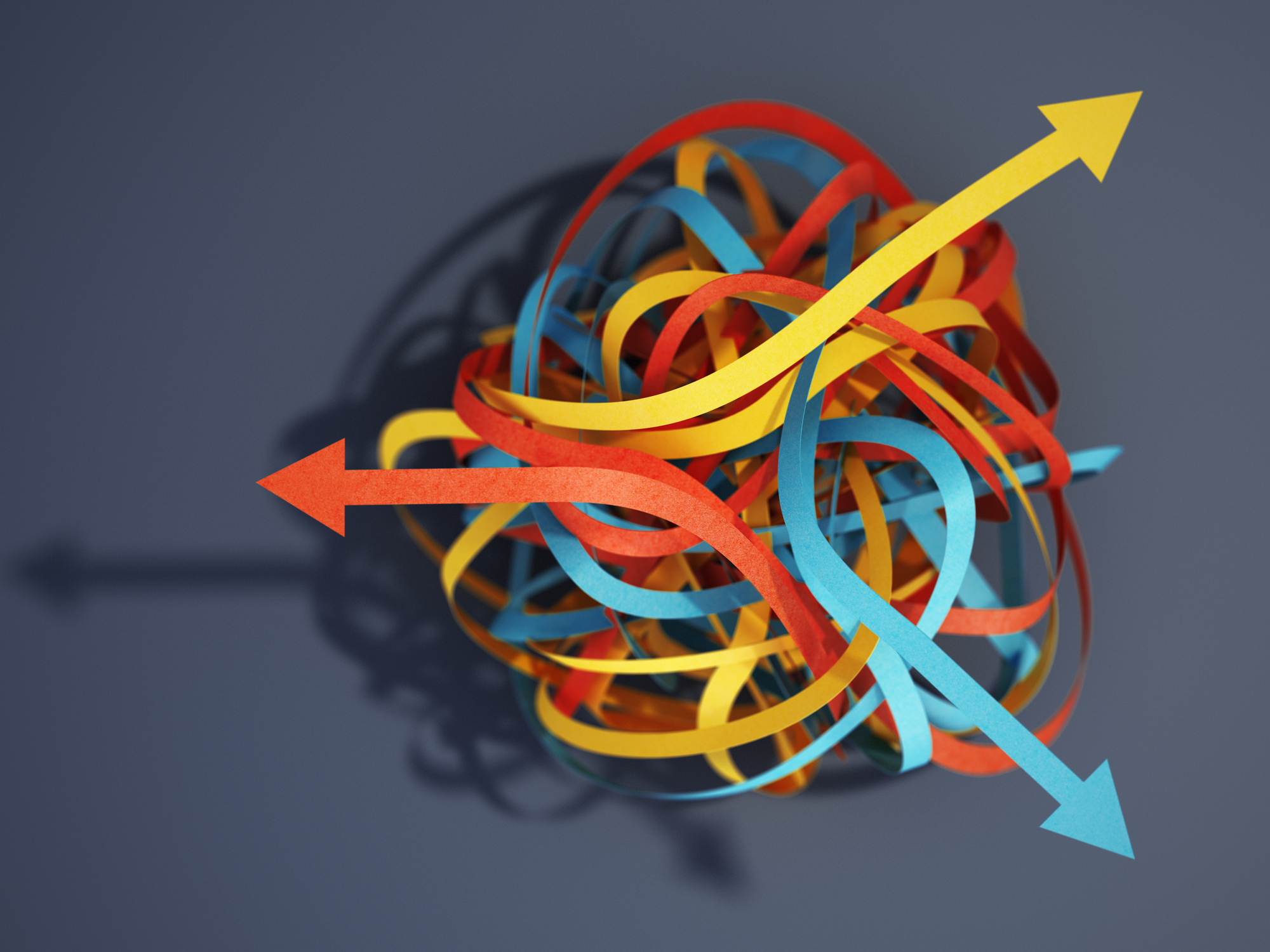 Tangled paper cut blue, yellow and red tapes with arrows pointing different ways. Choice and decisions concept.