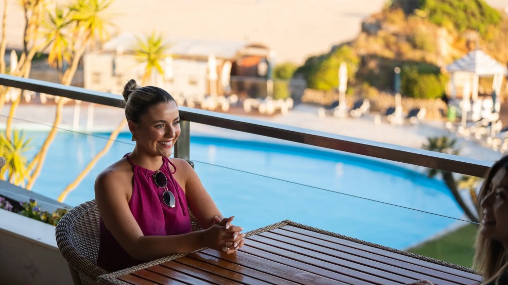 woman seated or a terrace overlooking the Hotel Algarve Solved Praia da Rocha swimming pool, ocean view 