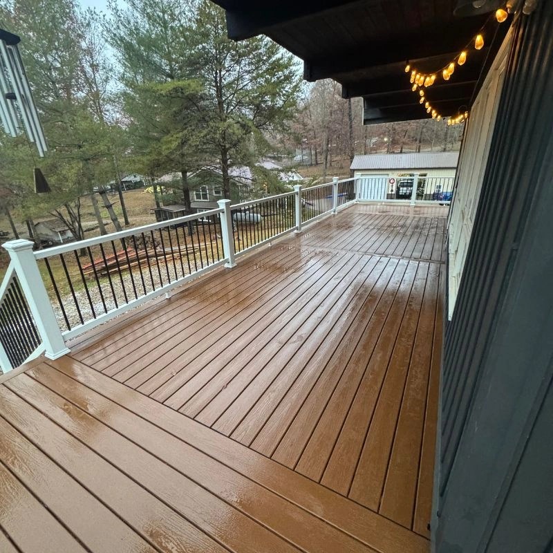 An expansive brown outdoor platform with white perimeter railings stretching along a dark grey house exterior.