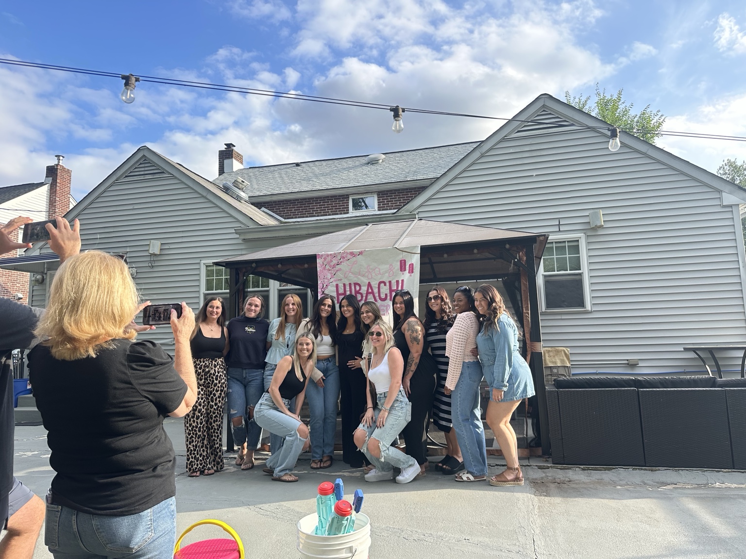 A group posing together in a decorated backyard before an outdoor celebration
