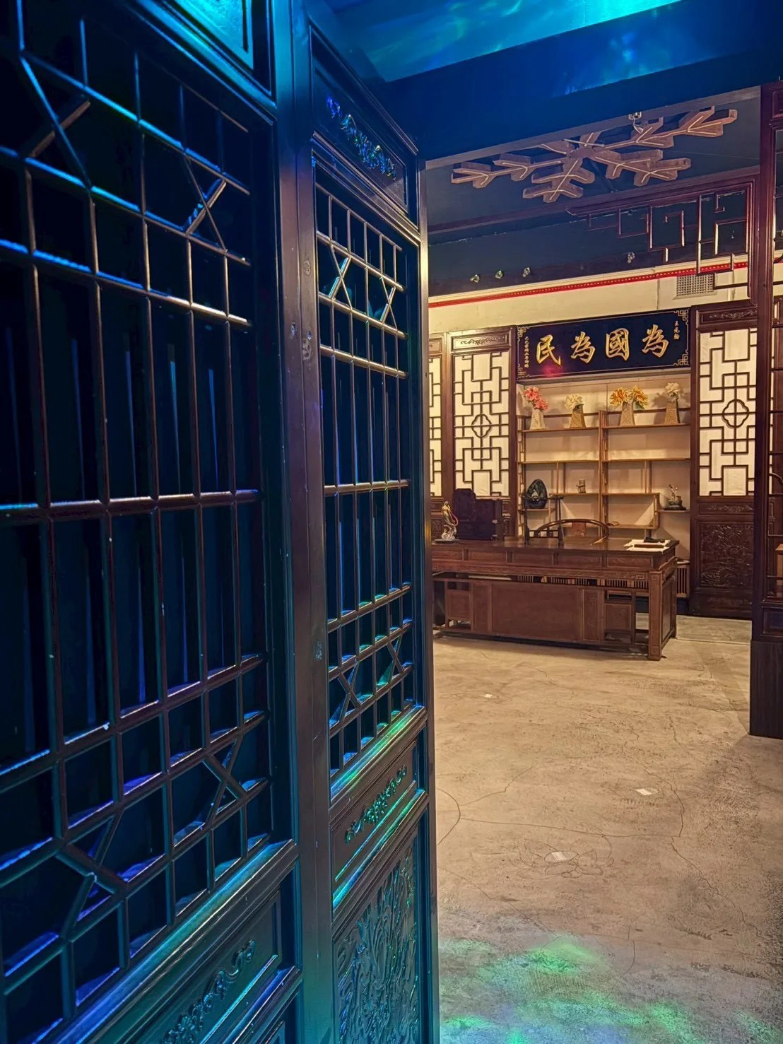 錦衣御行密室的雕花木格門後是一整座衙門大堂，青藍色燈光打在木格與匾額上