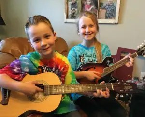 Boy with guitar and girl with mandolin learning to play instruments