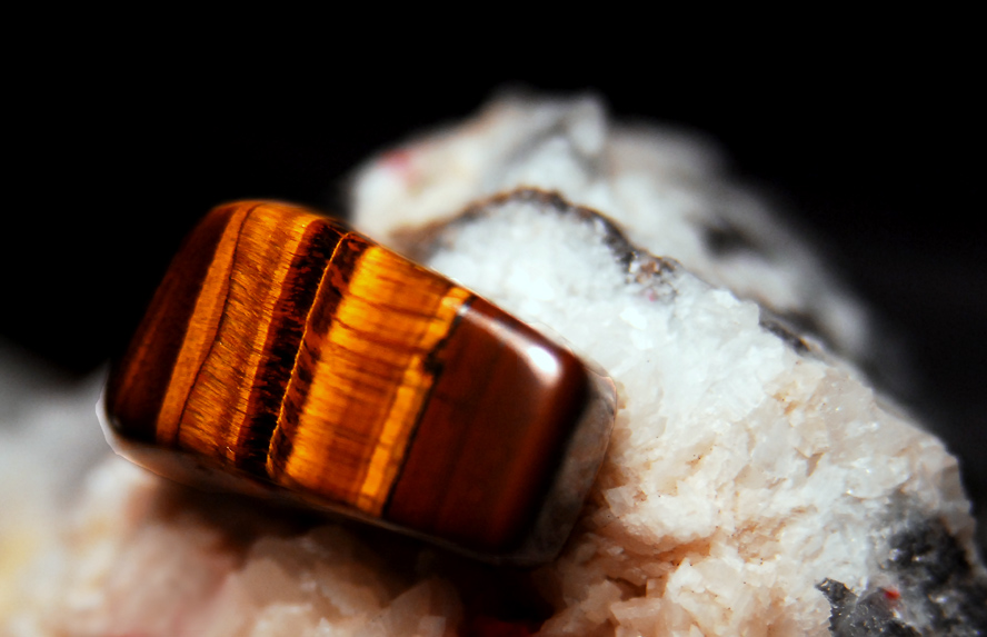Cómo las rocas y los minerales juegan con la luz para producir colores impresionantes 6 Una piedra preciosa de ojo de tigre encima de una roca.