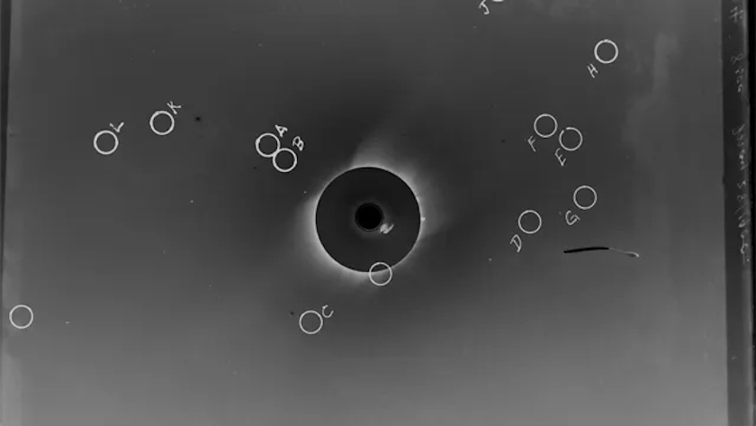 A black and white photograph shows a solar eclipse with handwritten letters and circles marking reference points—evidence from the event that helped Einstein change the facts about our understanding of gravity.
