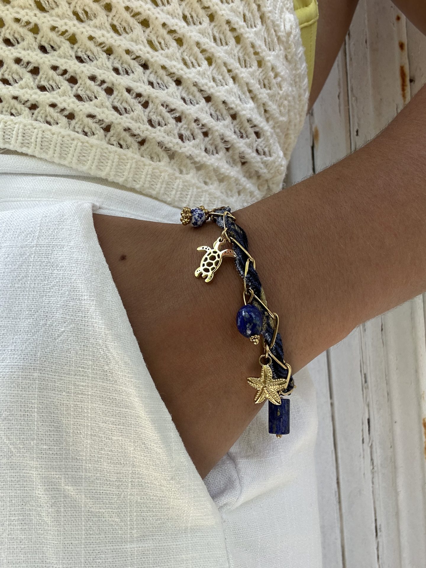 Bracelet Mystérieuse porté, ruban bleu marine et breloques bord de mer