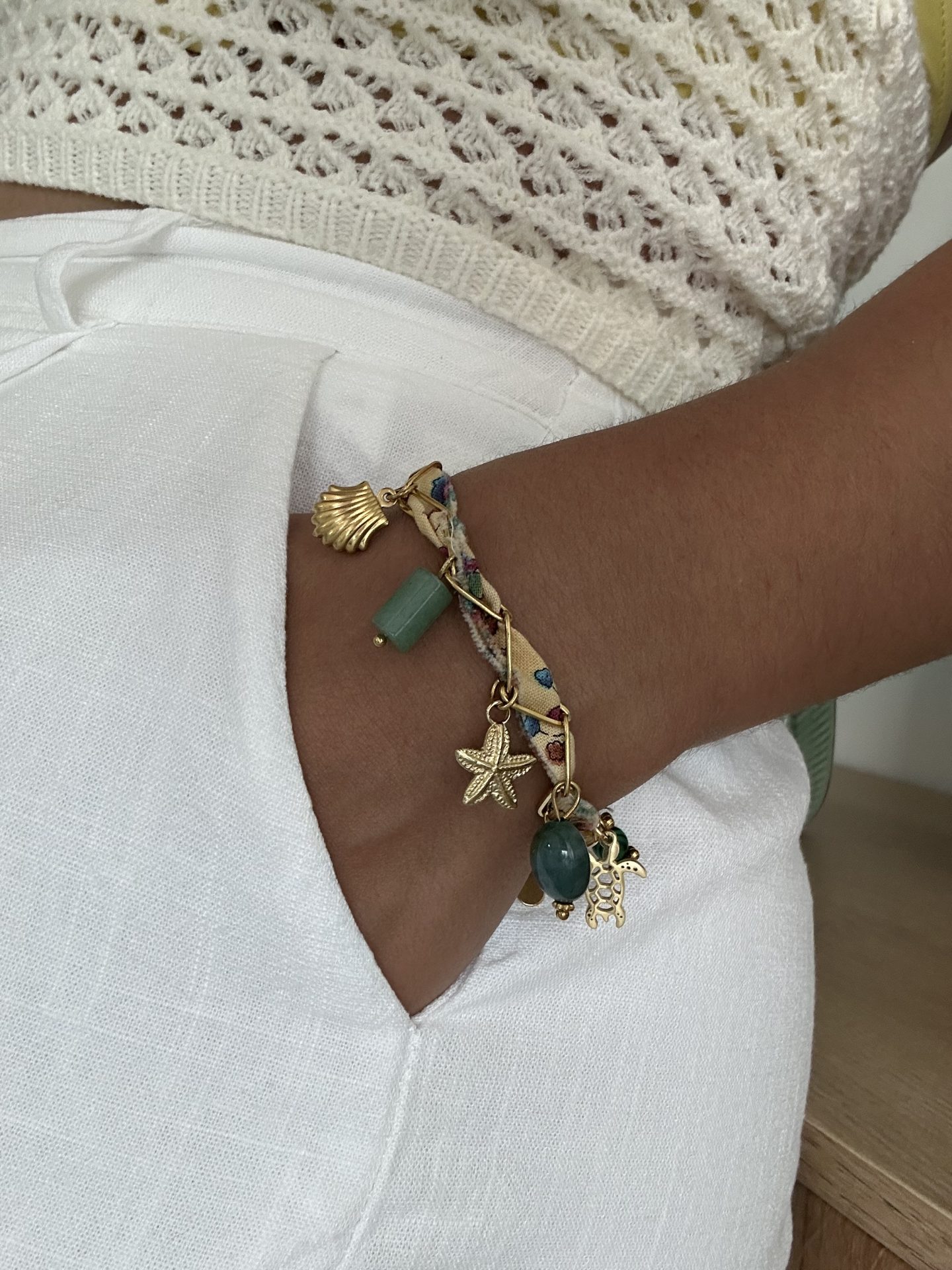 Bracelet Harmonieuse porté, ruban et breloques aux tons naturels et vert émeraude