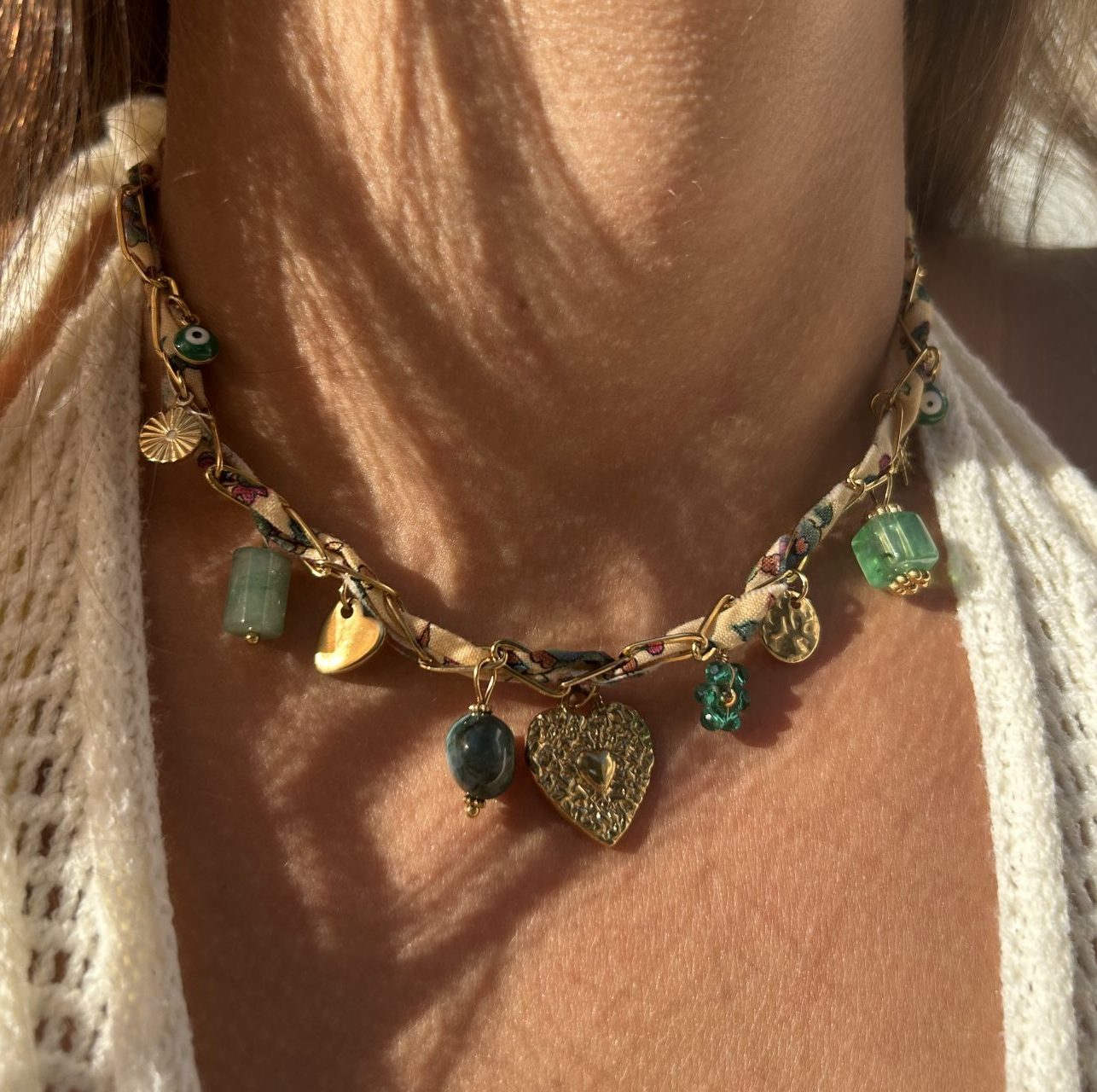 Collier Harmonieuse porté, ruban et breloques aux tons naturels et vert émeraude