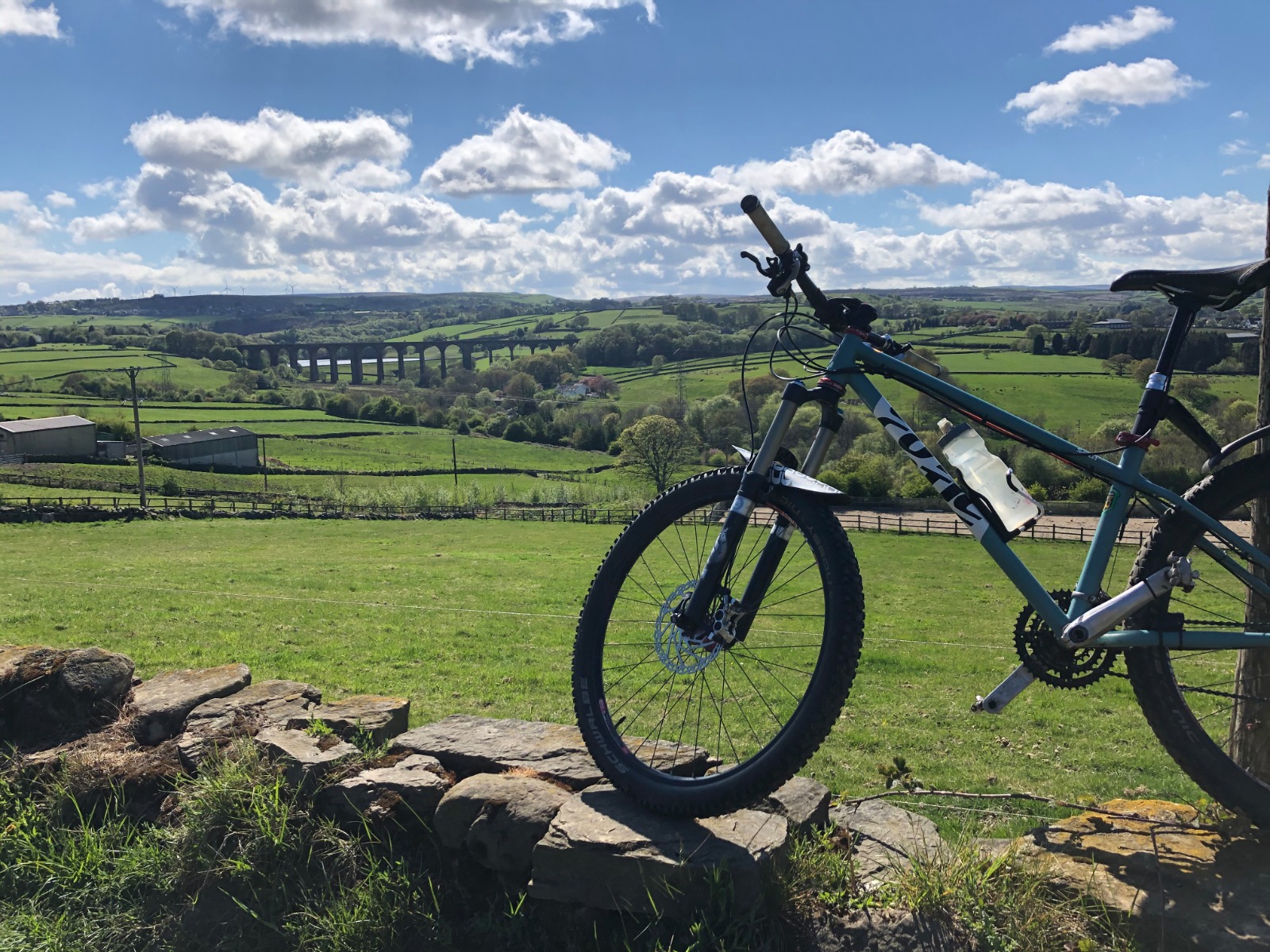 Bike on wall with viaduct in background.