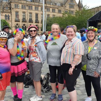 Six women with rainbow bike helmets and leis.