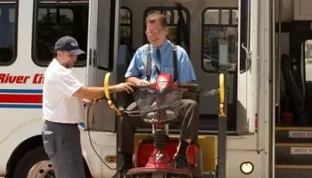 helping a man with special needs out of a bus