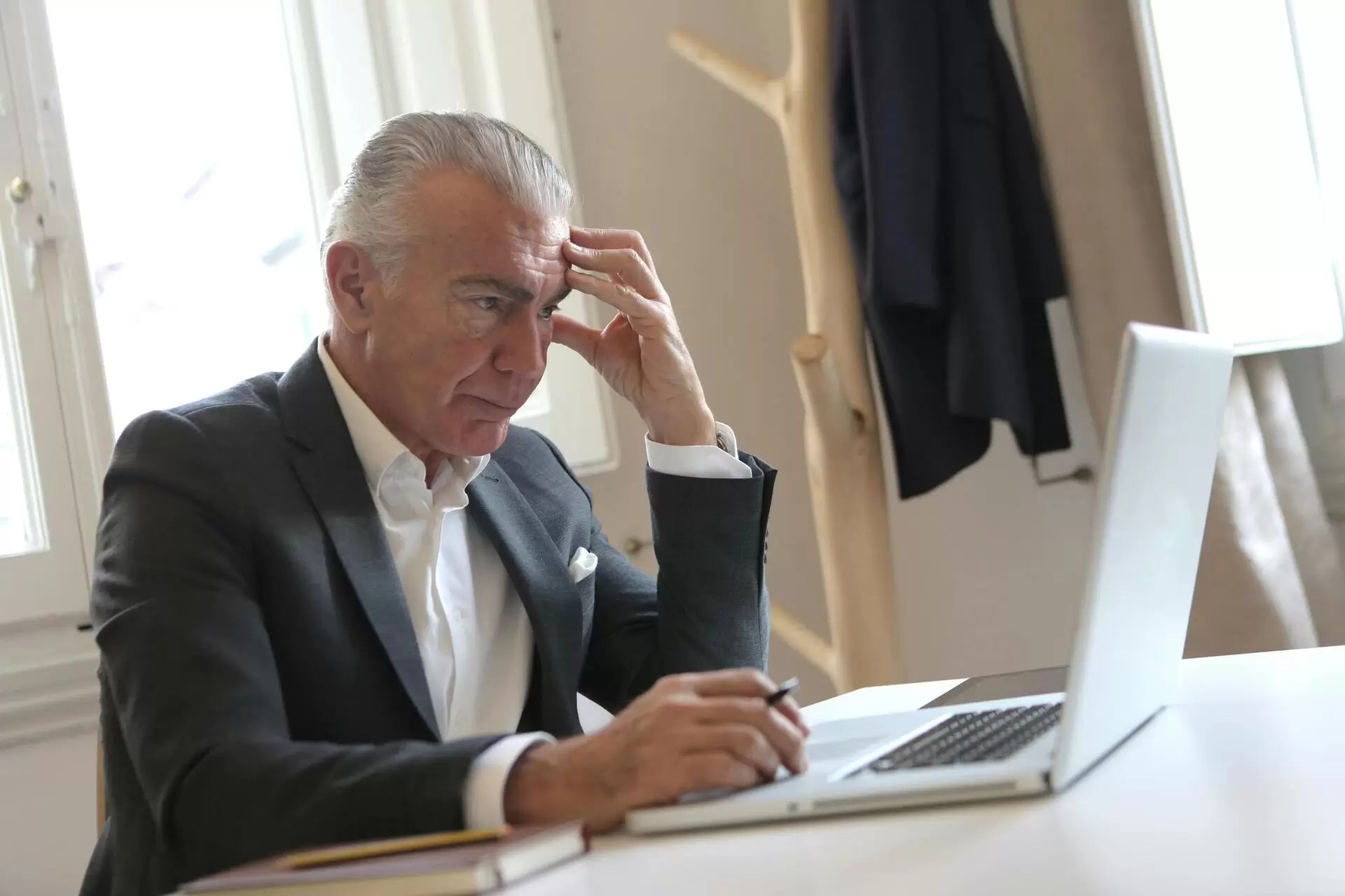 man in a suit stressed using his laptop