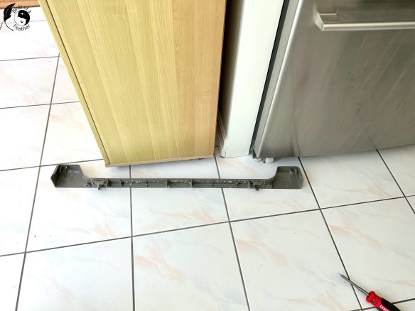 Front grate from fridge removed and on floor