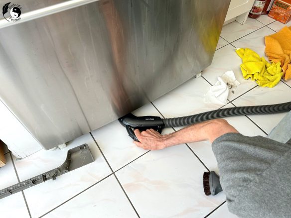 Vacuuming under the front of the fridge