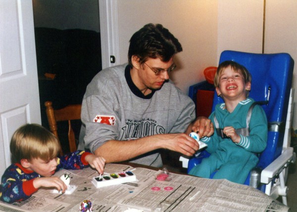 Eric and Aaron, now four years old, are busily at work dyeing Easter eggs with their dad, Richard.