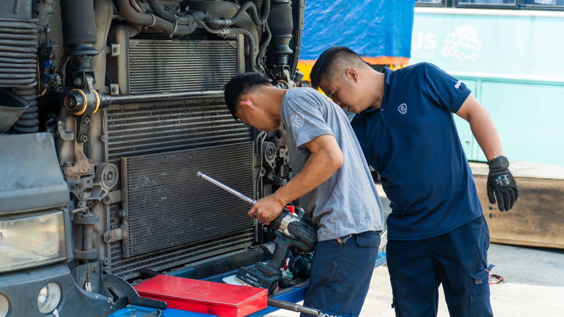 Two mechanics work intently on Scania radiator.