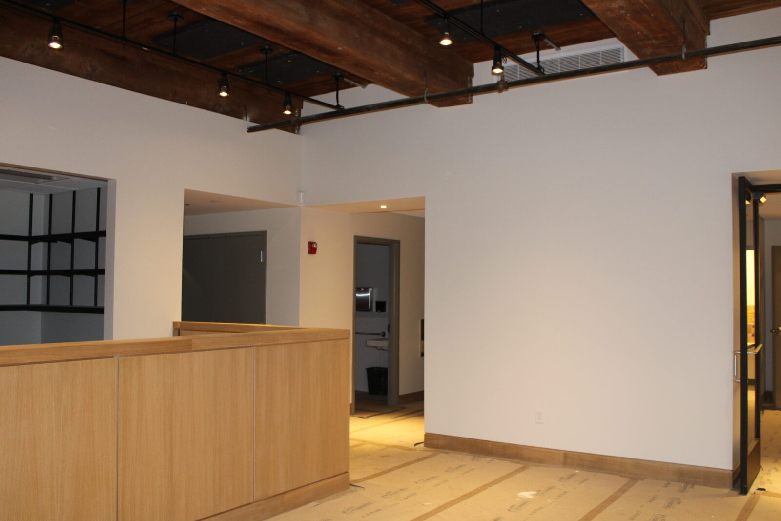 Interior view of the Industrial History Center in Amesbury, featuring a wooden reception desk, modern lighting, and a spacious, unfinished layout emphasizing the building's community-focused design.