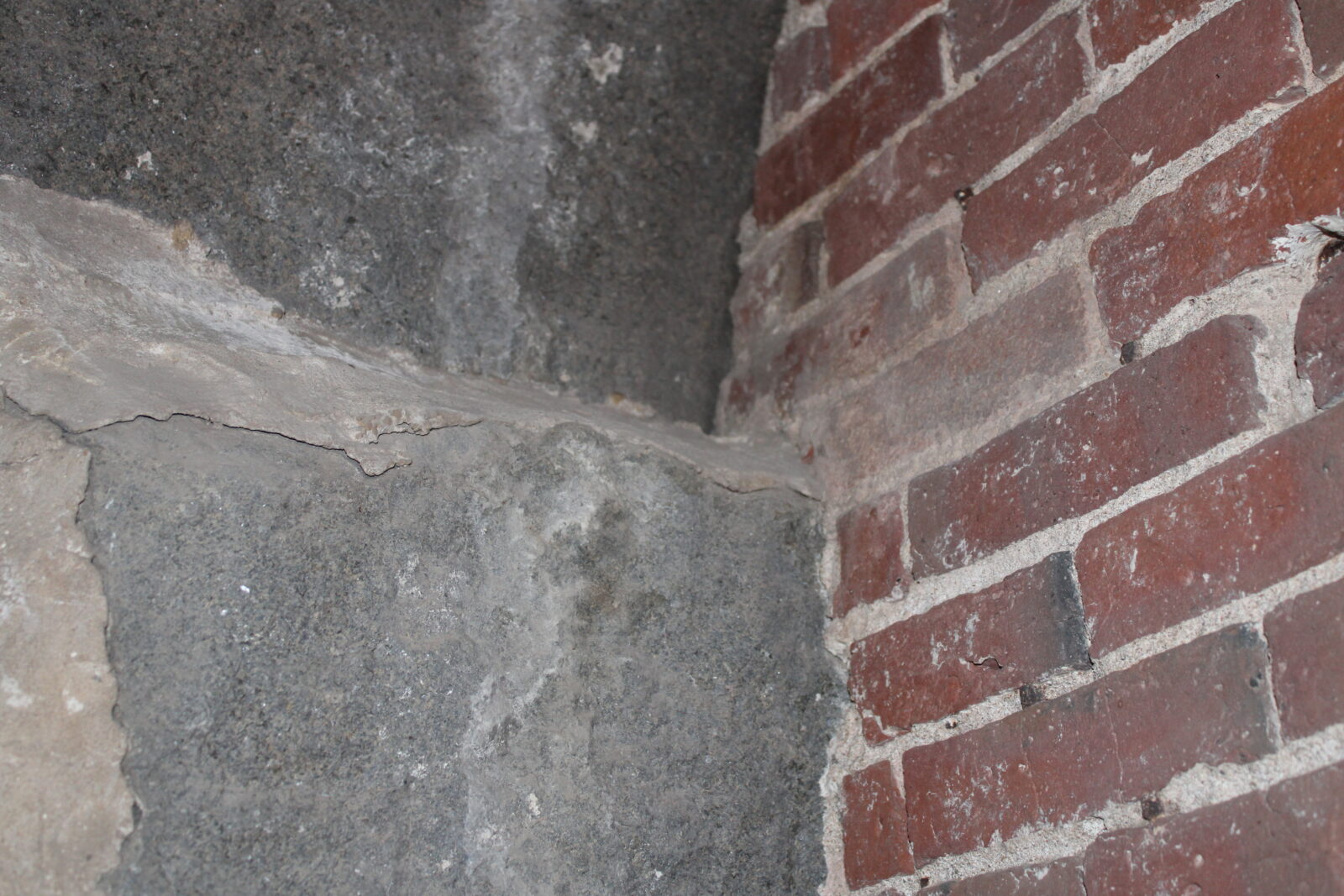 Corner of a brick wall and stone foundation in the Industrial History Center, showcasing historical construction materials relevant to Amesbury's industrial heritage.