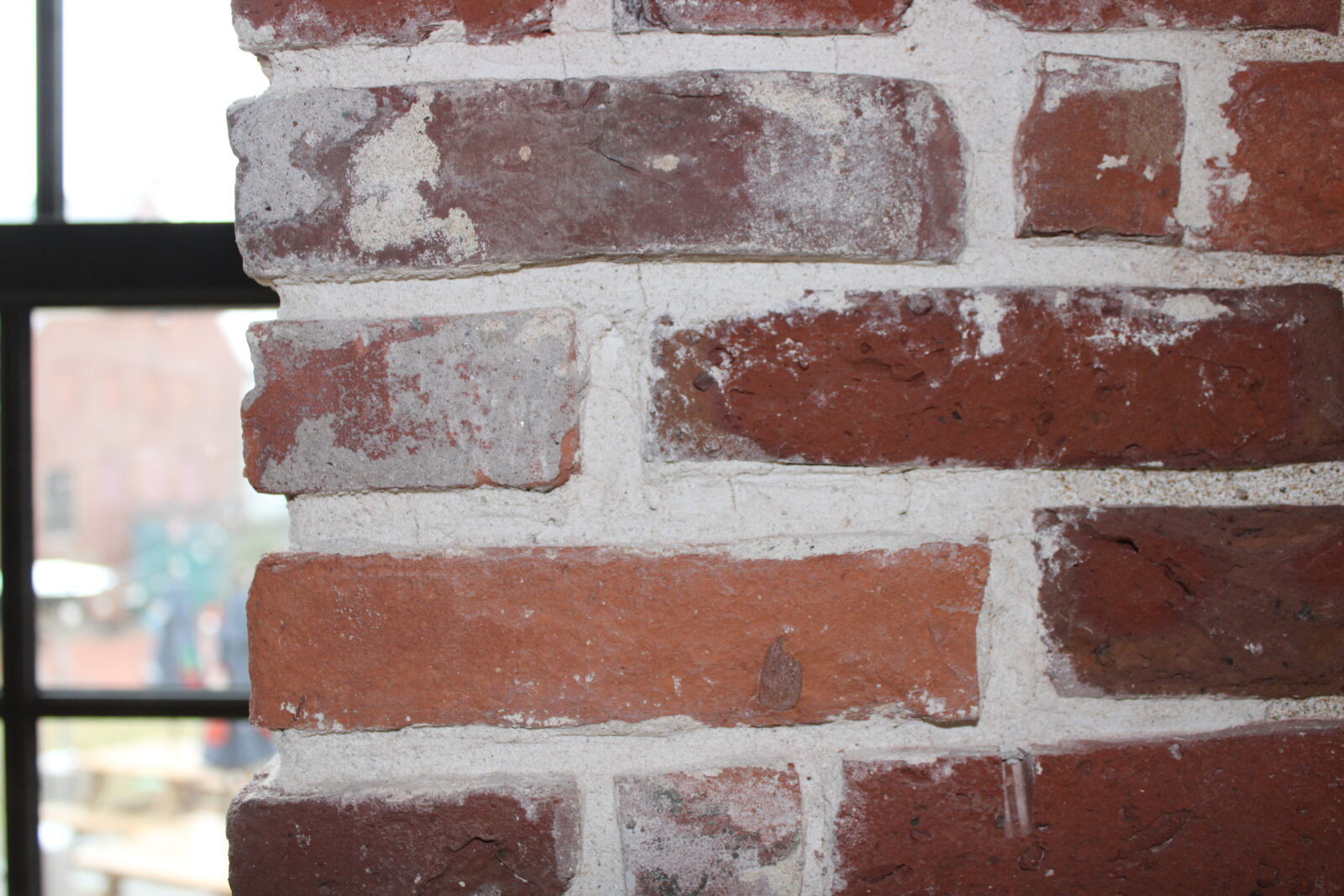 Brick wall featuring a mix of red and gray bricks, highlighting the industrial aesthetic of the Amesbury Carriage Museum's new space.