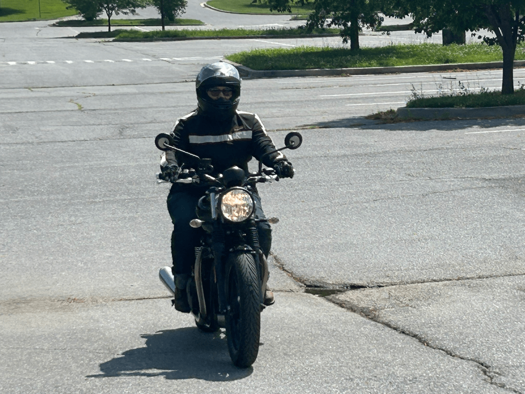 Author riding a motorcycle at slow speeds in a parking lot
