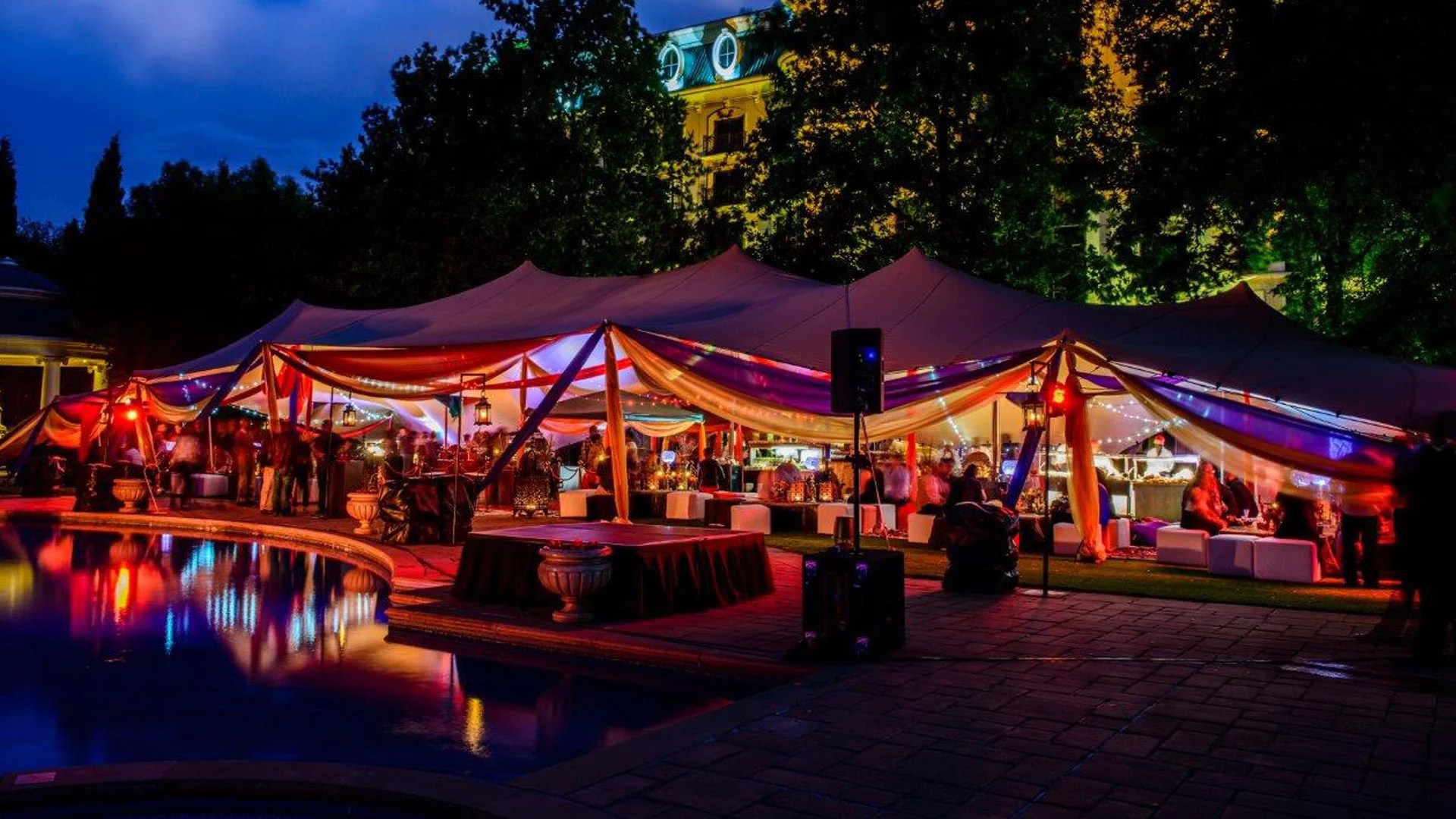 Sfeervol avondfeest onder een verlichte stretchtent bij een zwembad