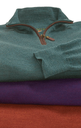 Stack of folded sweaters in green, purple and rust