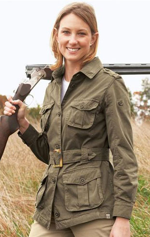 Smiling woman in an olive field jacket with a gun over her shoulder