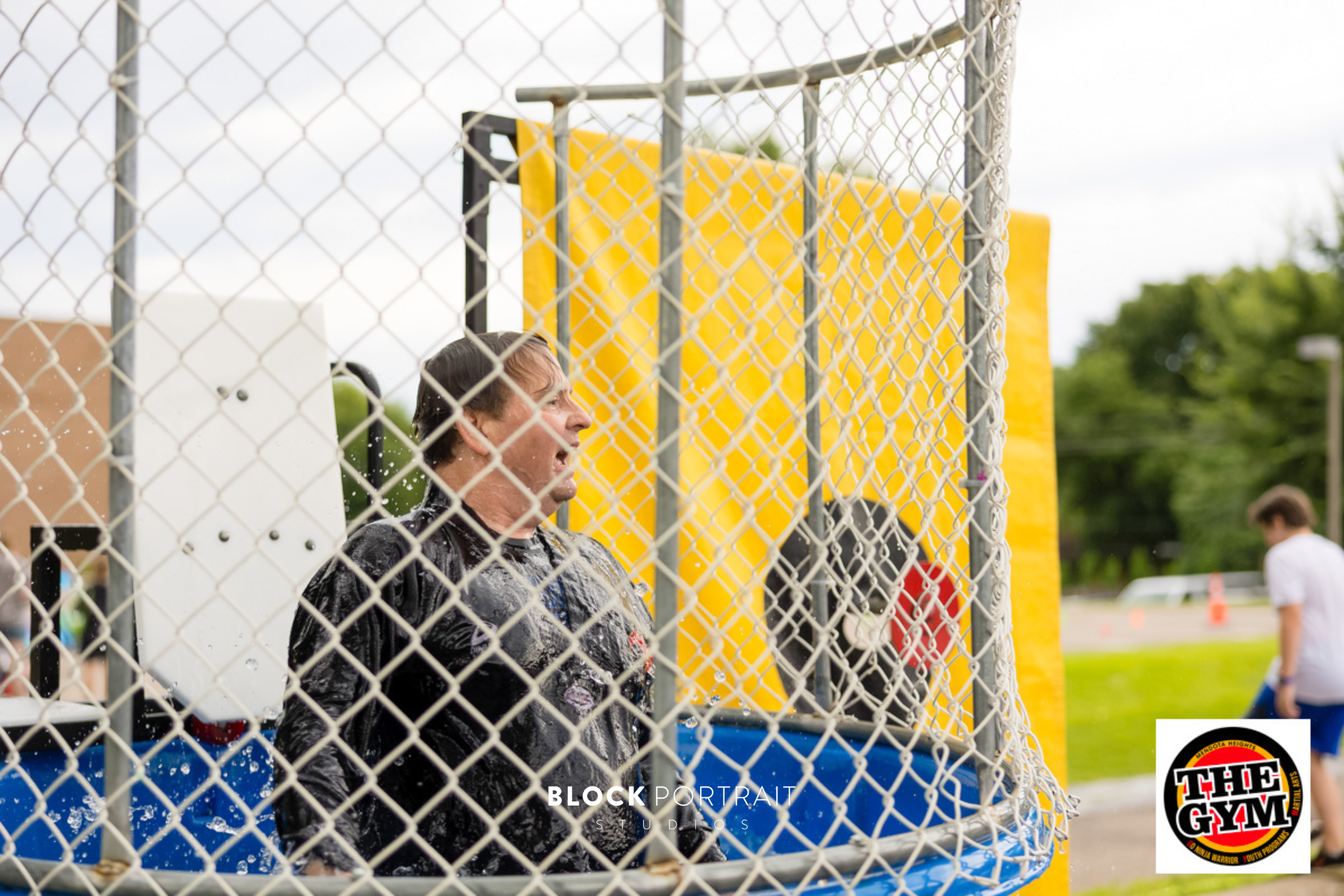 A Taekwondo master in a black uniform standing in a dunk tank after going under.