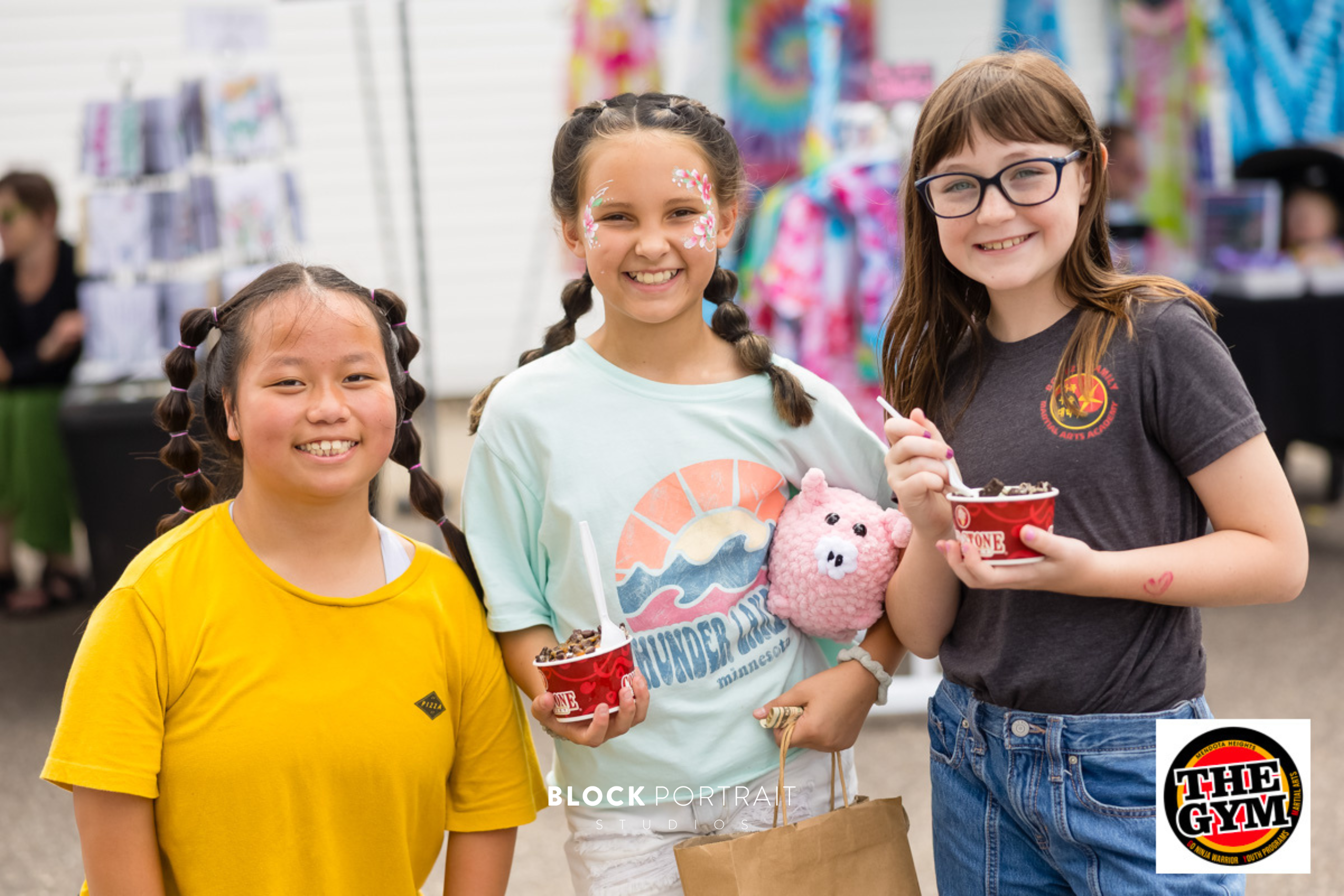 Three young girls holding Cold Stone ice cream cups and smiling.