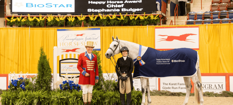 Happy Horse Award winner Stephanie Bulger standing for the awards photo with her horse Chief and the ringmaster at the Pennsylvania National Horse Show | BioStar US