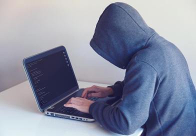 anonymous hacker with on laptop in white room