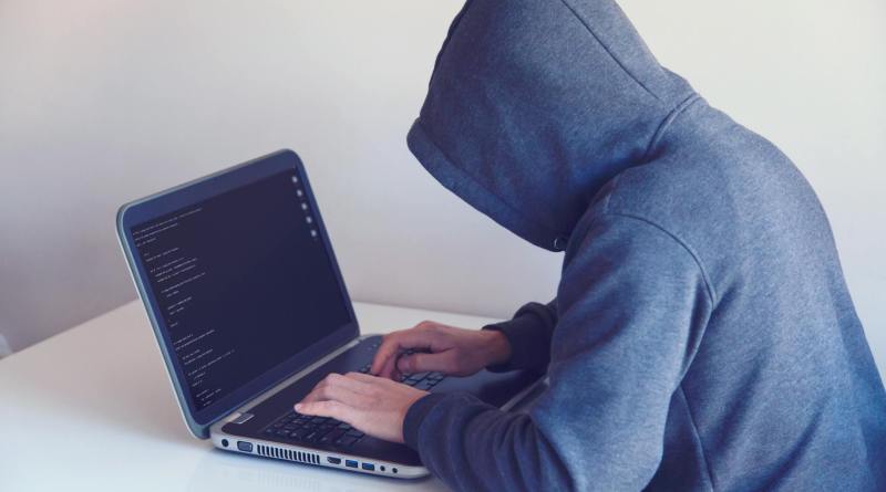 anonymous hacker with on laptop in white room
