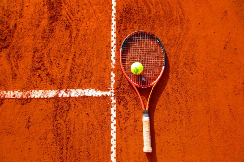 Tennis racket with tennis ball on clay court