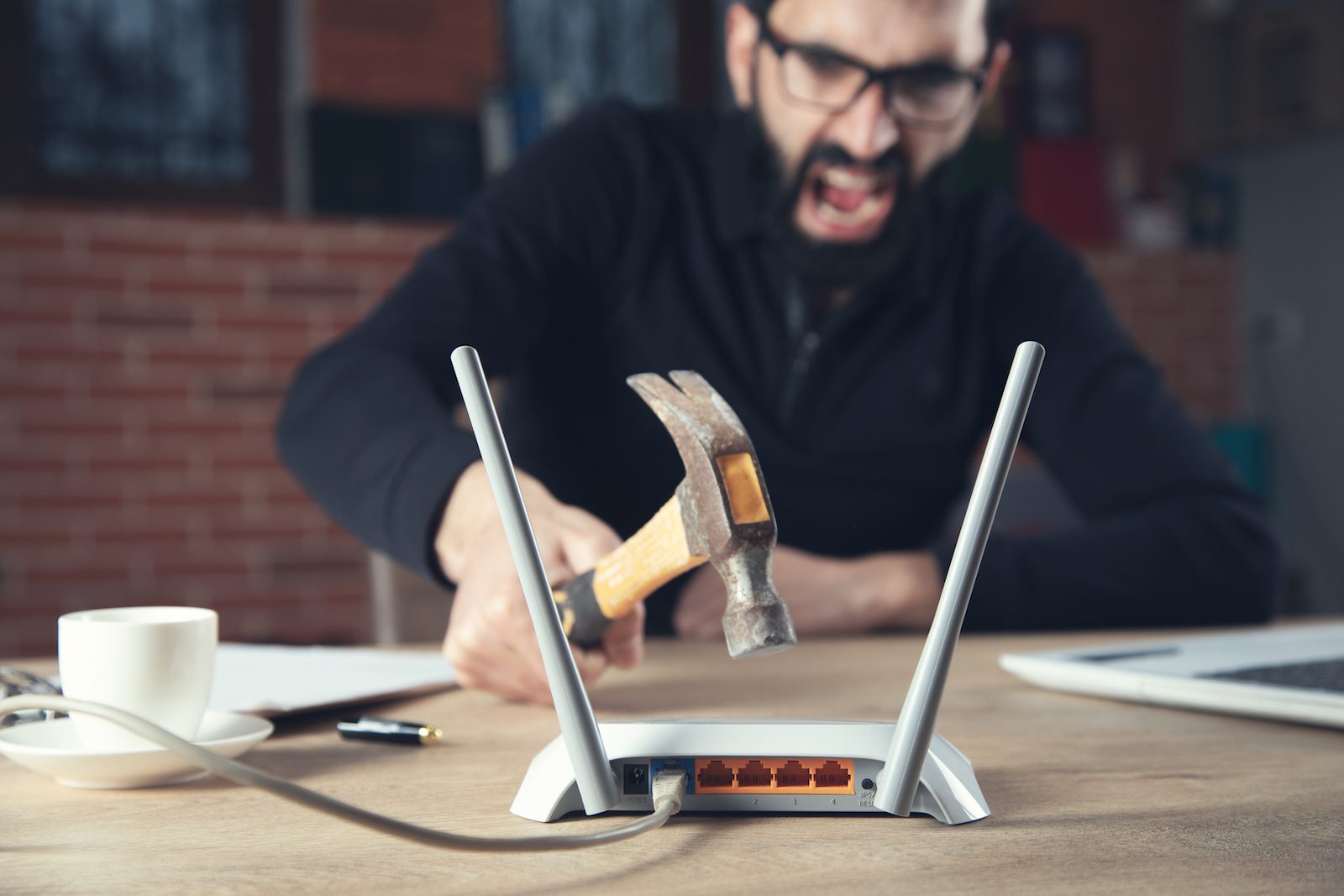 An angry man with a hammer about to hit his Wi-Fi router—bricking your Nighthawk router can be frustrated. Avoid issues with FlashRouters