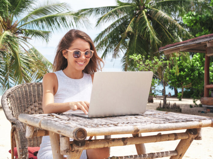 Young woman on laptop in the tropics - Look local when working remotely abroad