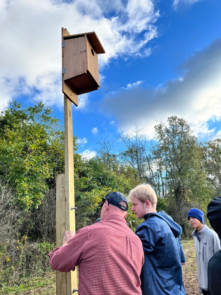 An Eagle Scout and his Scoutmaster put the final touches on installing a kestrel box.