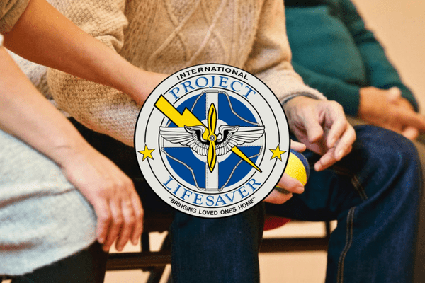 This image shows an elderly person sitting near a younger person who is offering a supporting hand. The logo for Project Lifesaver is layered overtop.