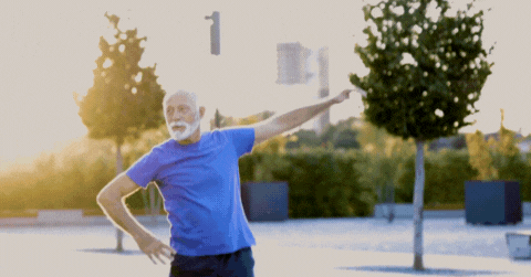 GIF: Short video of an elderly caucasian man doing arm stretches in the park.