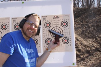 Dave Dolbee holding a Springfield EMP 4 pistol in front of a paper target