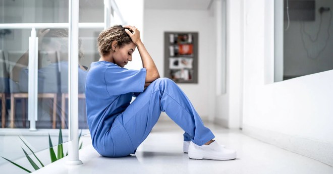 Asistentă medicală stând pe o masă albă, încercând să se relaxeze 