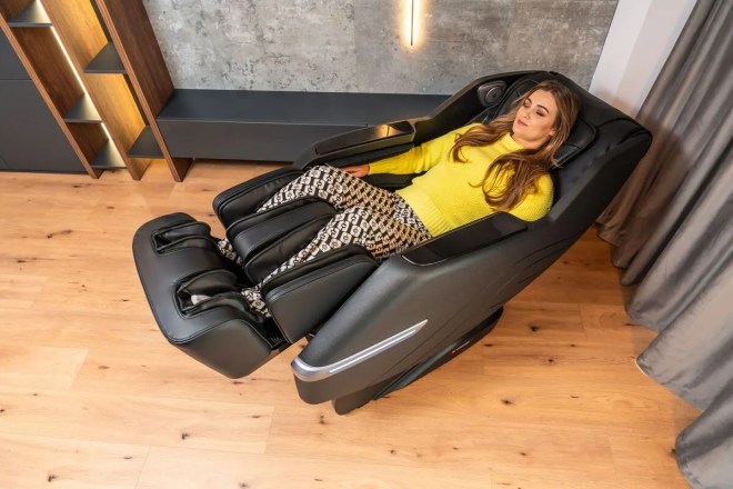 Fotoliu de masaj Vector de la Komoder, varianta pe culoarea neagră, cu un model feminin într-un interior de apartament