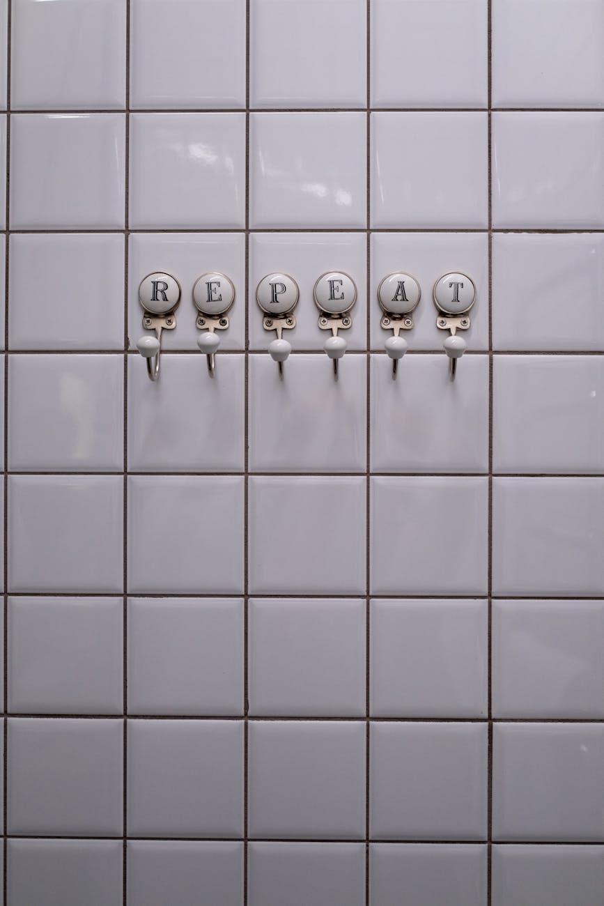 close up of towel hangers with letters attached to the tiles in a bathroom