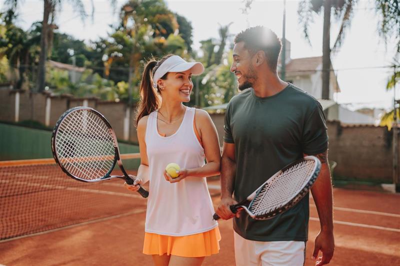 Happy couple on a sunny day playing tennis