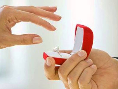 Main de femme prête à saisir une bague de fiancailles dans un écrin rouge présenté par un homme