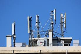 Antenne 4G et équipements de télécommunication sur le toit d'un bâtiment contre un ciel bleu.