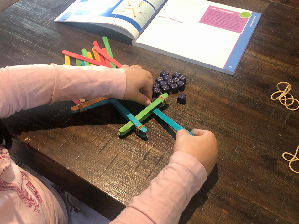 A young child sitting at a table and using icy pole sticks to test out activities from More Hands-On Science.