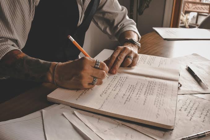 Man writing a journal with yellow pen