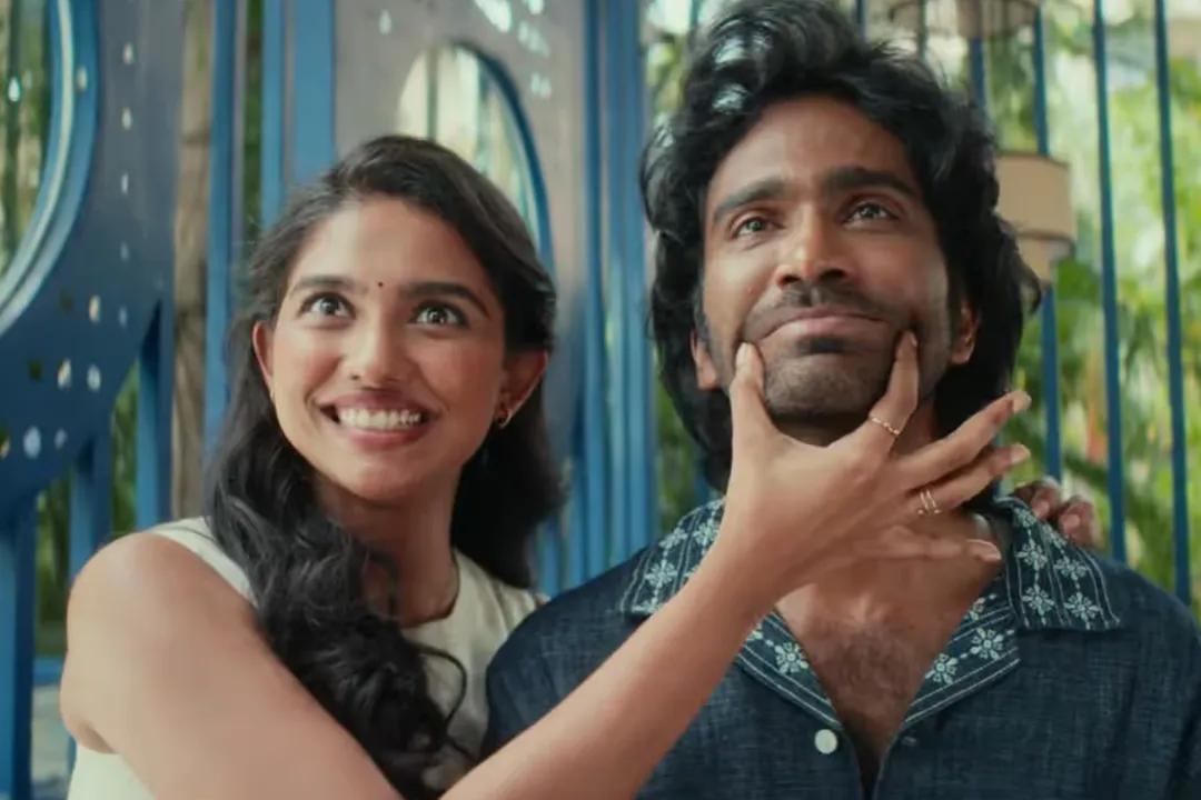 A playful romantic scene from the Dude 2025 film featuring Mamitha Baiju smiling while pinching Pradeep Ranganathan's cheeks.