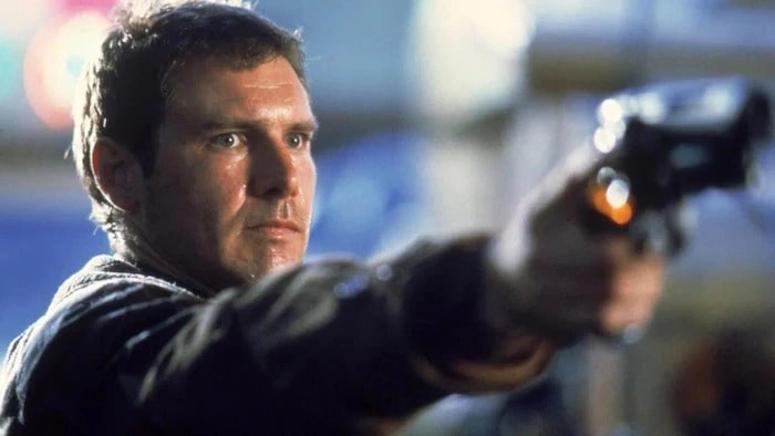 Close-up of Harrison Ford aiming a blaster in Blade Runner, illustrating precise framing derived from a director's shot list.